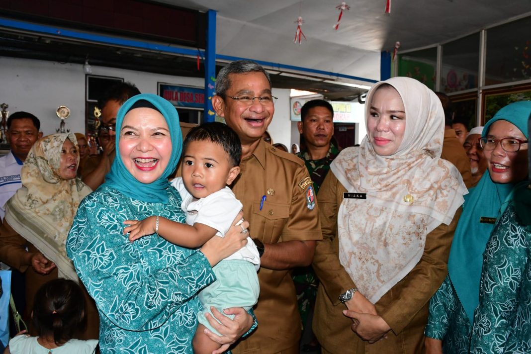 Pj Bupati Deliserdang Wiriya Alrahman dan Pj Ketua TP PKK, Ny Ismiralda Wiraya didampingi Kadis P3AP2KB Deliserdang Dr Dra Hj Miska Gewasari MM menggendong anak pada acara peninjauan ruang kelas PAUD di Lubukpakam, Senin (2/9/2024). (Dok/Kominfo Deliserdang)