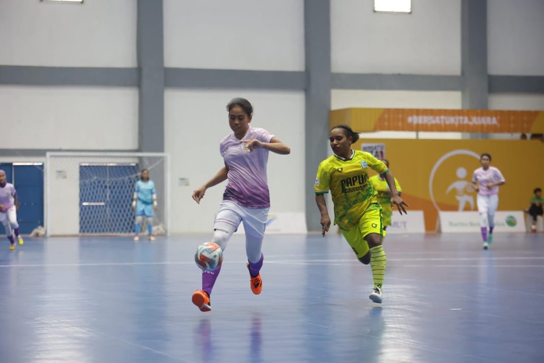 Pemain Futsal Putri Sumut Ni Kadek (kiri) berusaha mengejar bola meski mendapat kawalan dari pemain Papua Pegunungan pada babak penyisihan PON XXI di GOR Futsal Dispora Sumut, Selasa (3/9/2024). (Dok/Media PON)