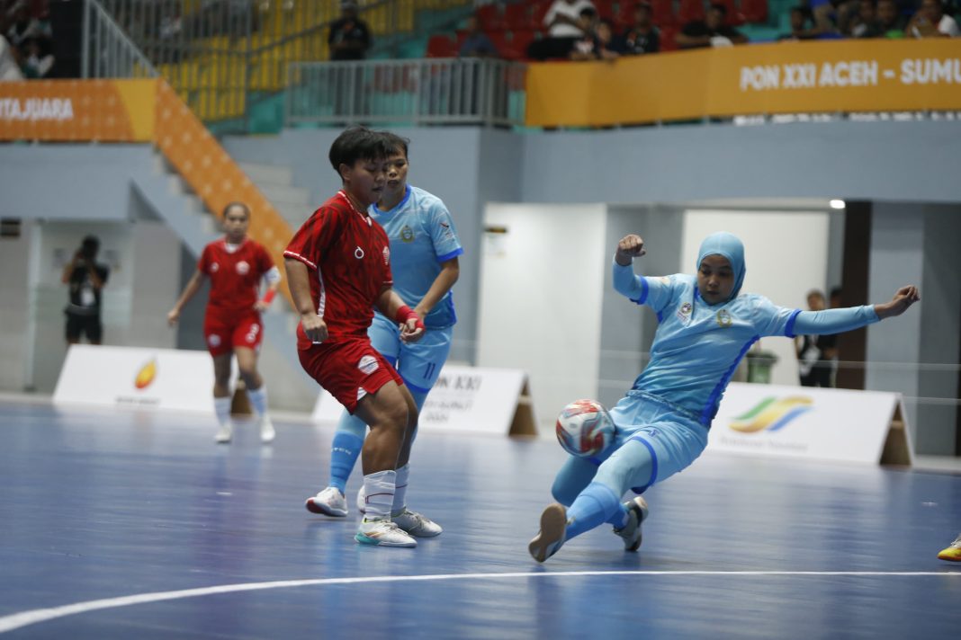 Pemain futsal putri Sumut (kanan) menahan gempuran pemain DKI Jakarta pada laga terakhir penyisihan PON XXI di GOR Futsal Dispora Sumut, Rabu (4/9/2024). DKI Jakarta menang 11-0. (Dok/PB PON)