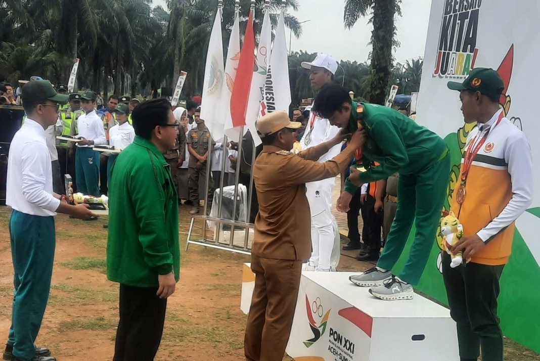 Bupati Sergai H Darma Wijaya mengalungkan medali kepada Muhammad Andi Royan, atlet balap sepeda Jawa Timur peraih medali emas di nomor Individual Time Trial Putra PON XXI, Selasa (10/9/2024).