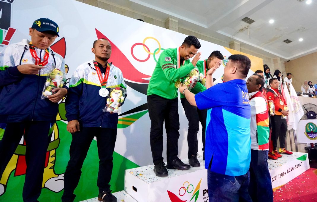 Ketua Umum Pengprov POBSI Sumut Salomo Pardede menyerahkan medali kepada Zefri Zein dan Punguan Sihombing, pebiliar Sumut nomor ganda putra di Pardede Hall Medan, Kamis (12/9/2024) malam. (Dok/Pengprov POBSI Sumut)