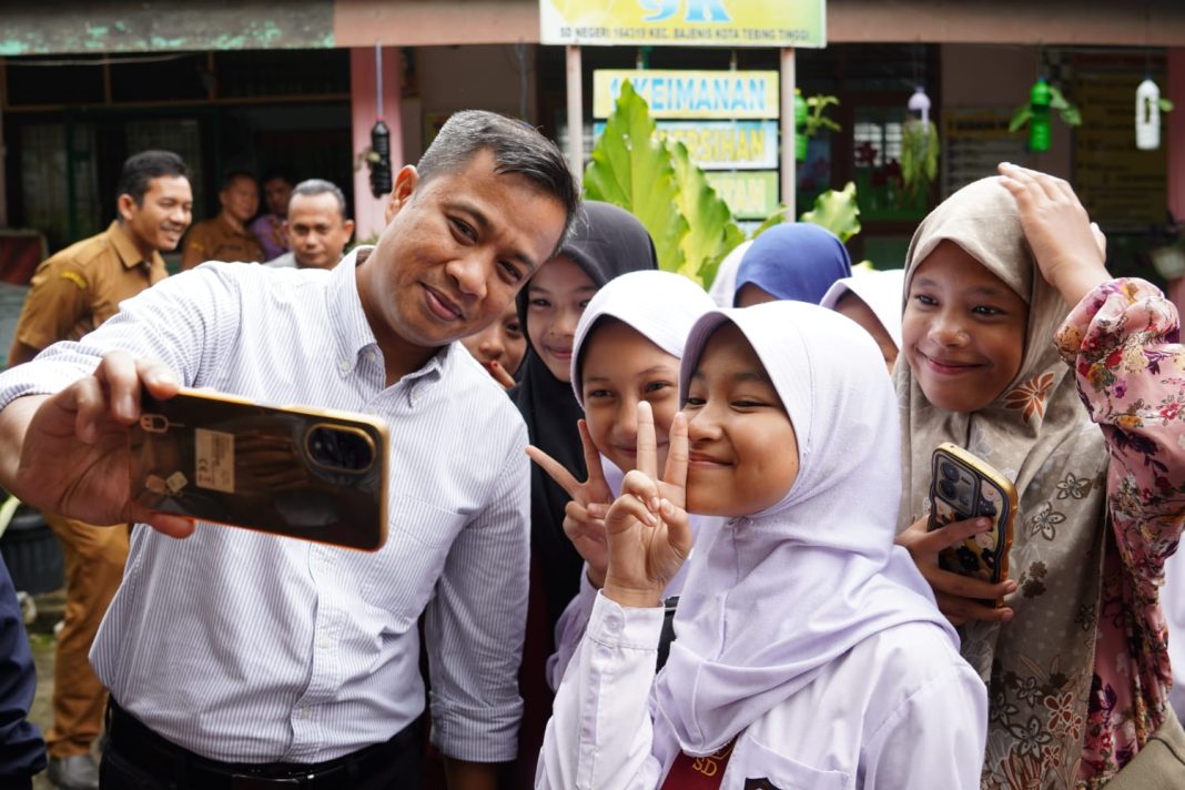 Pj Wali Kota Tebingtinggi Dr Moettaqien Hasrimi nampak melayani anak-anak yang mengajak swafoto dengan dirinya disela-sela dirinya memantau langsung pembelajaran digital di SD Negeri 164319, Kelurahan Bulian Kecamatan Bajenis, Selasa (24/9/2024). (Dok/Kominfo Tebingtinggi)