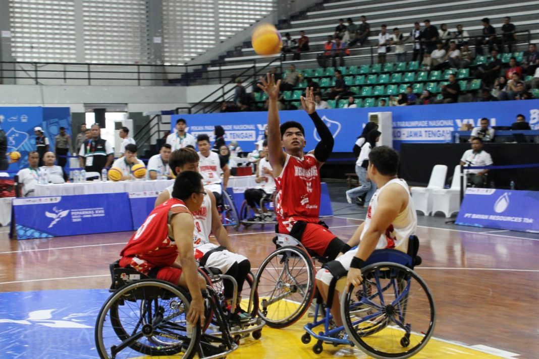 Pertandingan Exhibition Whell Chair Peparnas XVII antara tim Peparnas E (putih) melawan tim Peparnas C (14-merah) membawa bola, I Komang Saputra di Gor Sritek, Solo, Jawa Tengah, Rabu (9/10/2024). (Dok/PB Peparnas XVII)