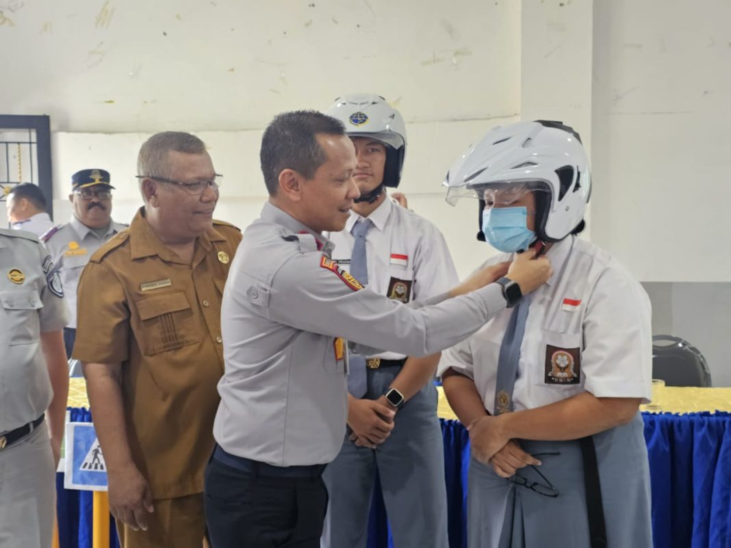 Kabid Lalu Lintas Dishub Sumut Ramli Simamora memasangkan helm kepada pelajar SMA/SMK di Medan, Selasa (22/10/2024). (Dok/Dishub Sumut)