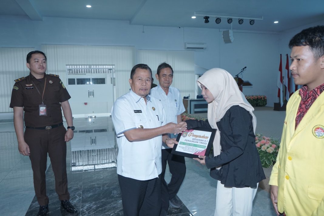 Asisten Bidang Administrasi Umum Drs Muhilli Lubis MM menyerahkan beasiswa kepada salah satu mahasiswi berprestasi dari keluarga tidak mampu secara simbolis. (Dok/Kominfo)