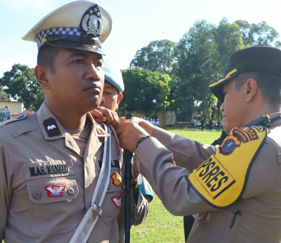 Kapolres Pematangsiantar AKBP Yogen Heroes Baruno menyematkan pita kepada personil saat memimpin apel gelar pasukan Ops Lilin Toba tahun 2024 bertempat di Mako Brimob Kompi 2 Batalyon B Polda Sumut di Jalan Ahmad Yani, Jumat (20/12/2024). (Dok/Polres Pematangsiantar)