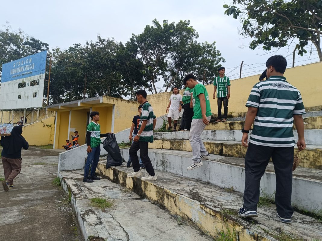 Suporter PSMS Medan melakukan aksi bersih-bersih stadion dengan mengutip sampah di tribune Stadion Baharoeddin Siregar saat pertandingan PSMS Medan melawan Sriwijaya FC dalam lanjutan Liga 2, Sabtu (11/1/2025). (Dok/Pewarta PSMS)