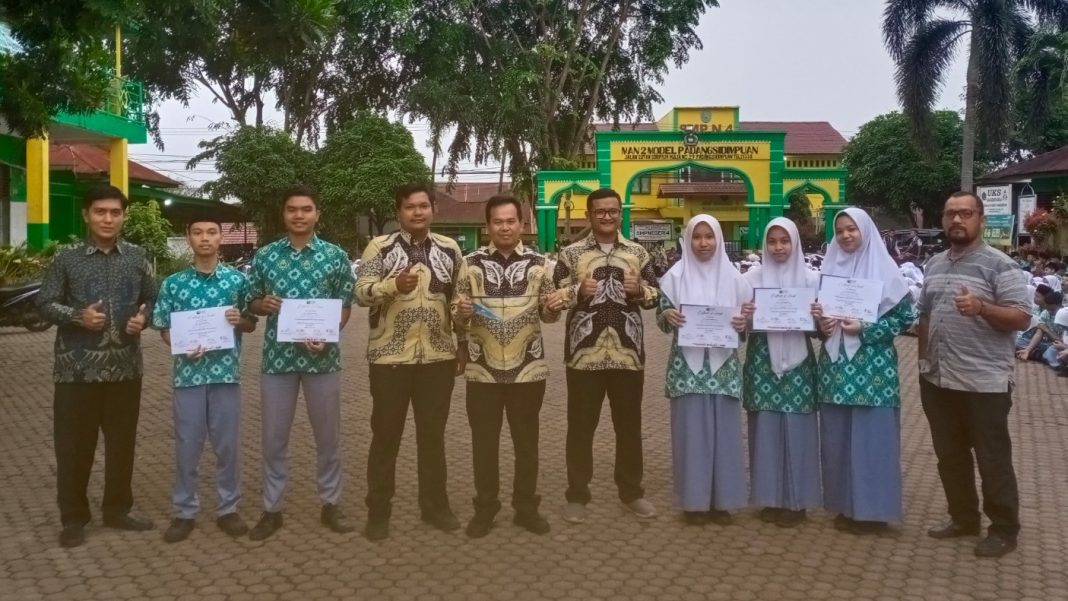 Tim riset MAN 2 Padangsidimpuan bersama guru pembimbing dan Kepala Madrasah berpose dengan sertifikat penghargaan usai menorehkan prestasi di tingkat internasional dengan meraih Medali Perak pada GYIIF 2025. (Dok/Kemenag)