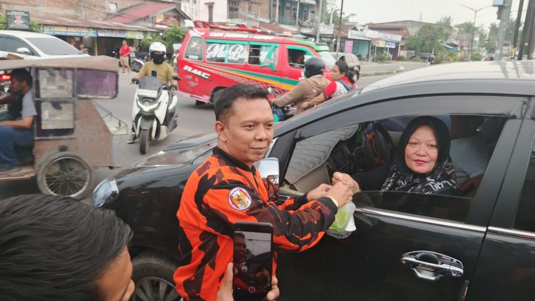 Ketua PAC Pemuda Pancasila Medan Tuntungan, Sempurna Sembiring, membagikan takjil kepada pengendara di Jalan Jamin Ginting, Kelurahan Kemengan Tani, Kecamatan Medan Tuntungan, pada Senin (10/03/2025).