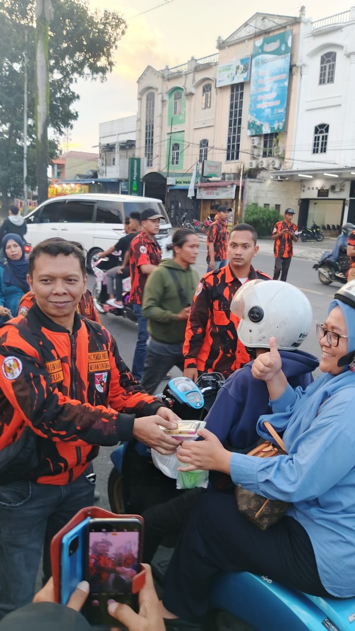 Seorang pengendara menerima takjil gratis dari anggota PAC Pemuda Pancasila Medan Tuntungan di Jalan Djamin Ginting, Rabu (12/3/2025).