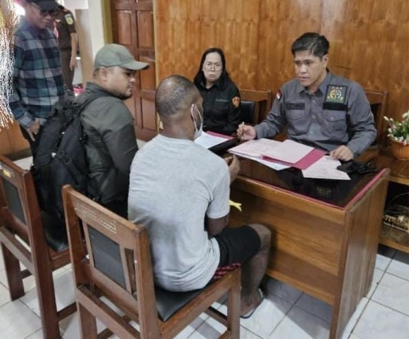 Petugas dari Satgas Ops Damai Cartenz-2025 saat menyerahkan tersangka Kamenak Gire ke Jaksa Penuntut Umum di Kantor Kejari Nabire.