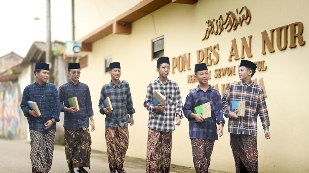 Sejumlah santri dengan pakaian khas pesantren membawa kitab saat berjalan di lingkungan Pondok Pesantren An Nur.
