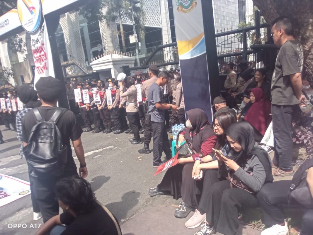 Barisan Polwan berdiri berjaga sambil memegang poster kecil saat aksi damai di depan Kantor DPRD Sumut, Kamis (1/5/2025).