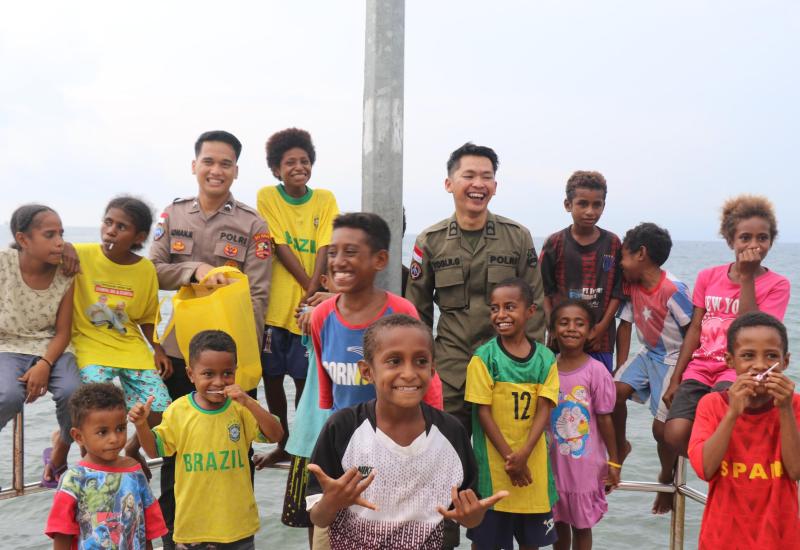 Personel Satgas Humas Operasi Damai Cartenz-2025 berfoto bersama anak-anak Kampung Nelayan Hamadi saat kegiatan silaturahmi dan pembagian sembako di Distrik Jayapura Selatan, Kota Jayapura, Senin (5/5/2025).