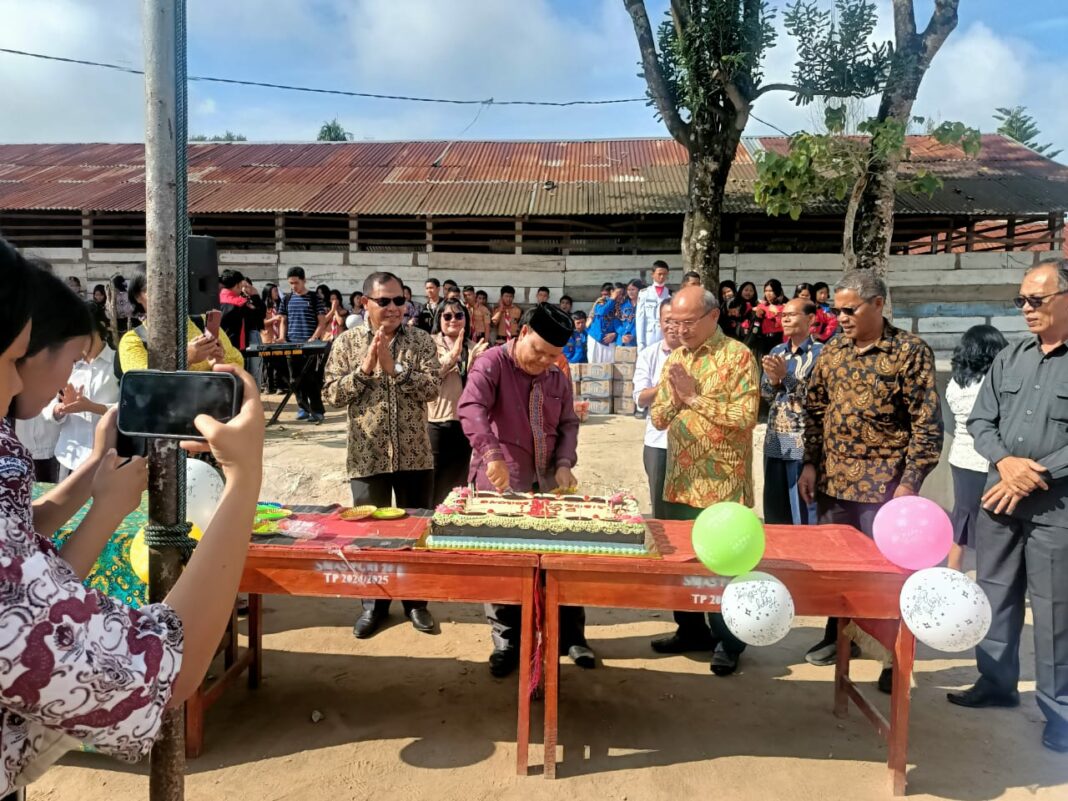 Kepala SMA PGRI 20 Siborong-borong Drs Alpa Simanjuntak MPd didampingi Alamsa Sihombing (kiri pakai kaca mata) saat memotong kue ulang tahun dan membagi-bagikannya kepada pendiri, guru, dan murid.